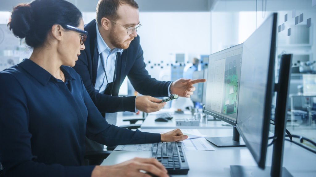 Male Supervisor talking to a female at a computer